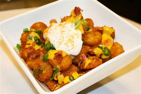 Totchos Tater tots smothered in cheddar cheese sauce with seasoned sour ...