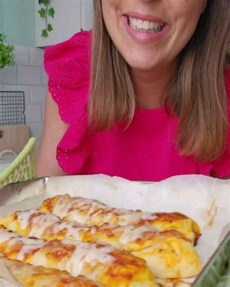 A Woman Sitting At A Table With Some Pizza In Front Of Her And Smiling