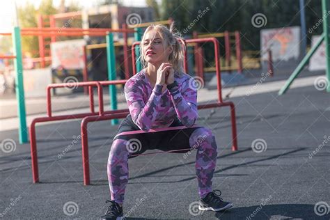 Beautiful And Athletic Blonde Girl Doing Squats On The Street Sports