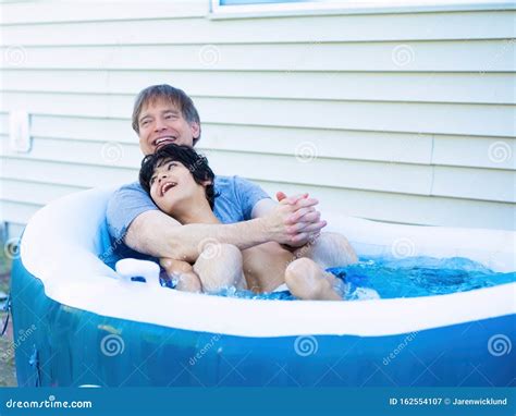 Father Sitting In Hot Tub With Disabled Son Outdoors Laughing Stock Image Image Of Race Happy