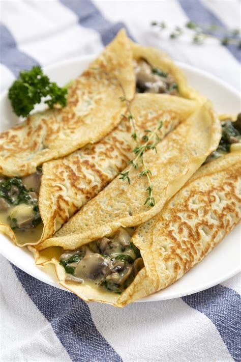 Savory Homemade Mushroom Spinach And Cheese Crepes On A White Plate On