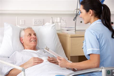 Nurse with senior male patient in bed - Maidstone and Tunbridge Wells