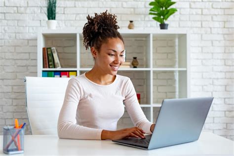 Woman Working On Laptop In The Office Looking At The Screen And Typing