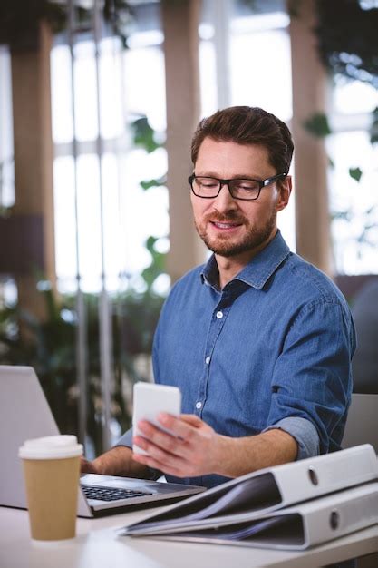 Premium Photo Businessman Using Cellphone While Working On Laptop At