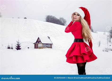 Merry Christmas Beautiful Blonde Woman In Red Dress And Santa Clause Hat On A Background Of