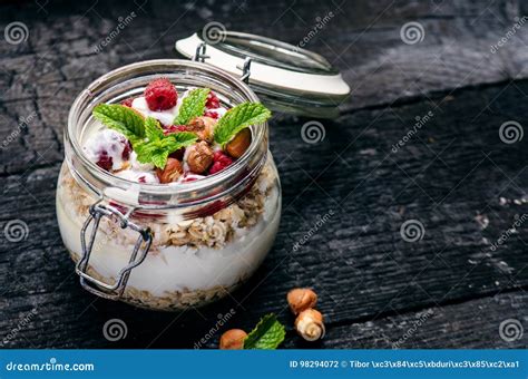 Full Jar Of Muesli Yogurt Raspberries Nuts On A Black Burnt Wood