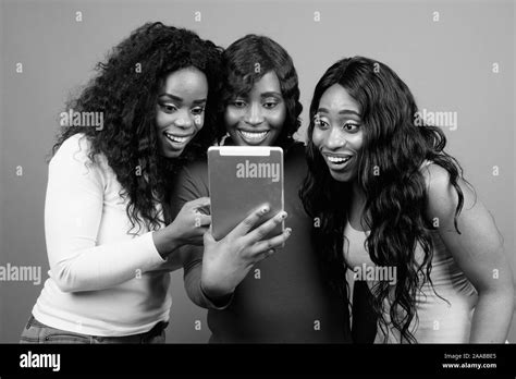 Young Beautiful African Twin Sisters And Friend Against Gray Background