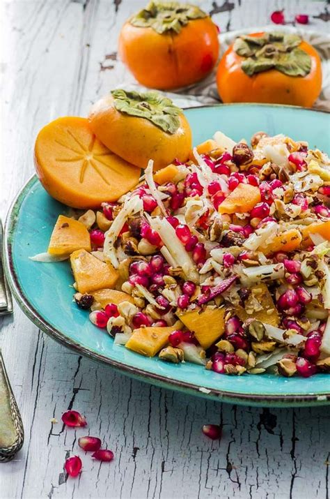 Persimmon Fennel Salad With Pomegranate Seeds And Hazelnuts On A Teal