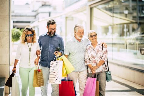 Group Of Four People Doing Shopping Together In A Mall Holding Shopping