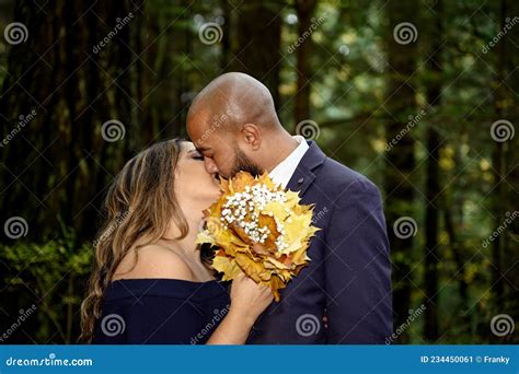 Photo Pleine Damour Dun Jeune Couple Mixte Affectueux Qui Sembrasse Dans Les Bois Image Stock