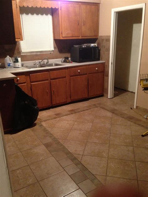 A Kitchen With Tile Flooring And Wooden Cabinets