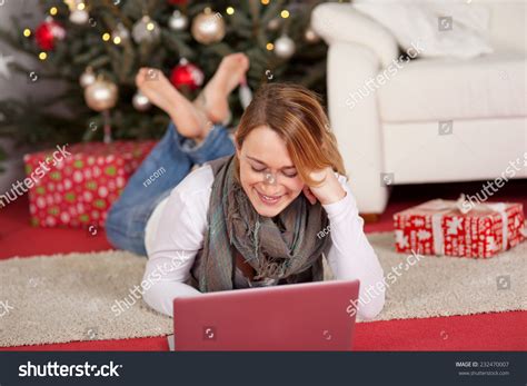 Young Woman Relaxing With Her Laptop In Front Of A Xmas Tree Lying