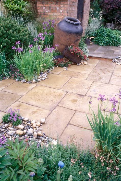 Stone patio with rustic urn, irises, spring flowering plants | Plant ...