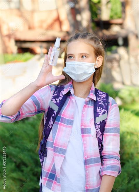 Little girl child with face mask and holding sanitizer. Education ...