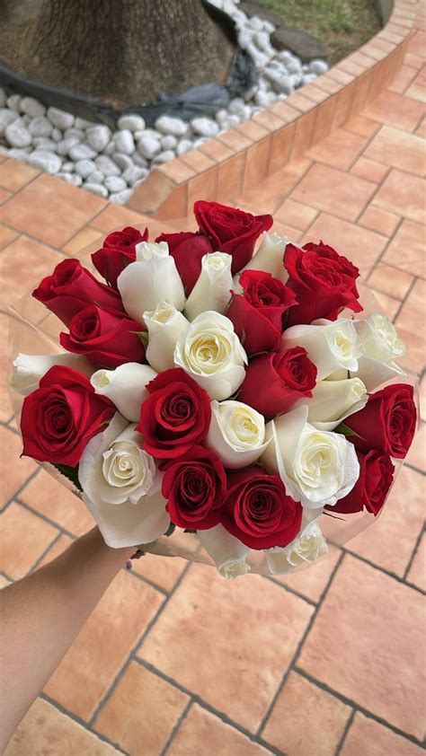 A Bouquet Of Red And White Roses In Someone S Hand On A Brick Walkway