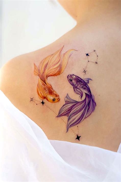 a woman's back with two goldfish tattoos on it