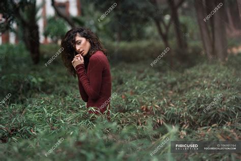 Brunette Woman Posing In High Grass And Looking At Camera Exotic Nature Stock Photo