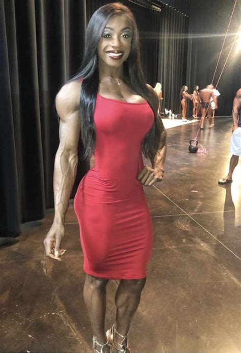 A Woman Posing For The Camera In A Red Dress With Muscles On Her Chest