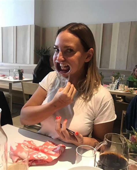 A Woman Sitting At A Table With Food In Front Of Her And Eating