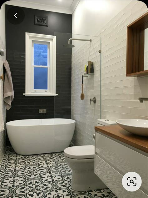 A White Bath Tub Sitting Next To A Toilet Under A Bathroom Window In A