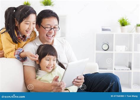 Pai Que Usa O Pc Da Tabuleta Com Meninas Foto De Stock Imagem De Casa