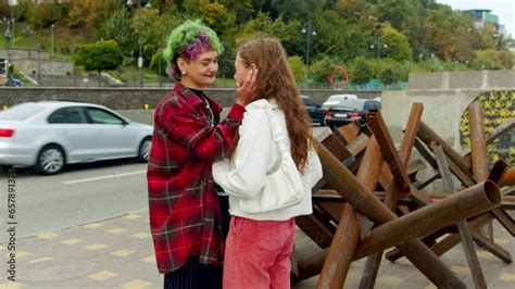 Vidéo Stock Two lesbian girls couple kissing in front of antitank hedgehogs in Kyiv Rainbow