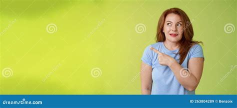 Excited Intrigued Middle Aged Mature Redhead Woman Pointing Gazing Left Side Copy Space