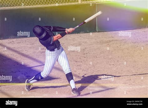 A Baseball Softball Player Is Swinging The Bat Hitting The Ball With