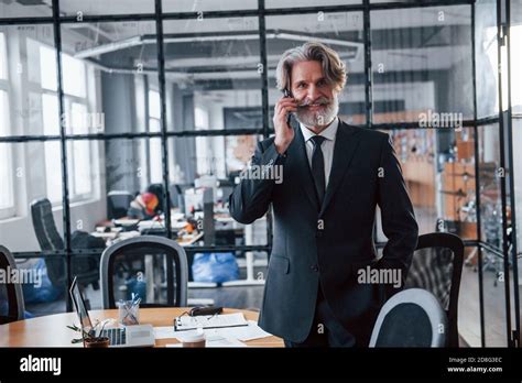 Mature Businessman With Grey Hair And Beard In Formal Clothes Have Conversation By The Phone In