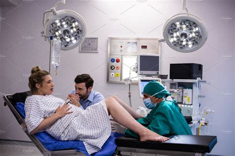 Doctor Examining Pregnant Woman During Delivery While Man Holding Her