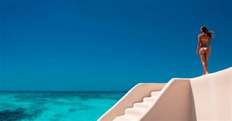 Premium AI Image Island Beauty Sensual Woman In Bikini Standing Against A Wall On A Paradise