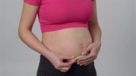 Close Up Unrecognizable Pregnant Woman Stands On A White Background