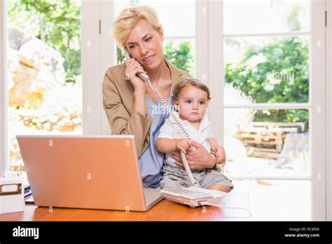 Pretty Blonde Woman With His Son Phoning And Using Laptop Stock Photo Alamy