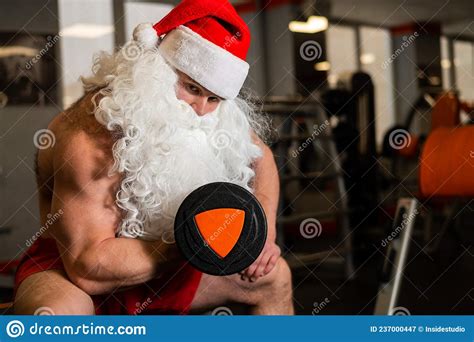 Santa Claus In The Gym Muscular Man With A Naked Torso Doing Exercises With Dumbbells Stock