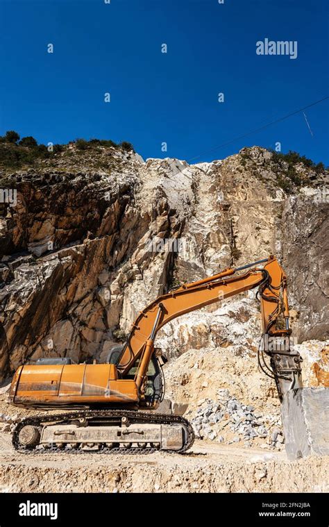 Orange Tracked Excavator With Jackhammer In A White Marble Quarry