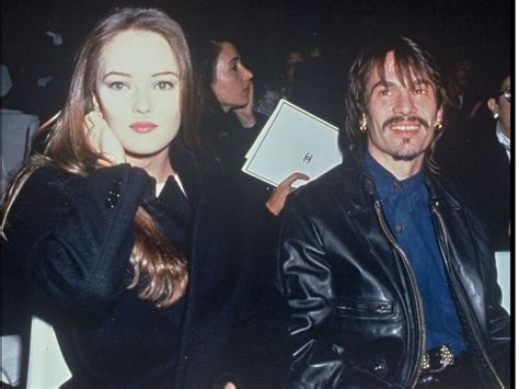 A Man And Woman Sitting Next To Each Other At An Event With People In