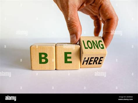 Be here belong symbol. Businessman hand turns a cube and changes words 'be here' to 'belong ...