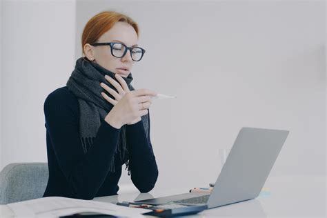 Young white woman is sick while working in office in scarf and looking