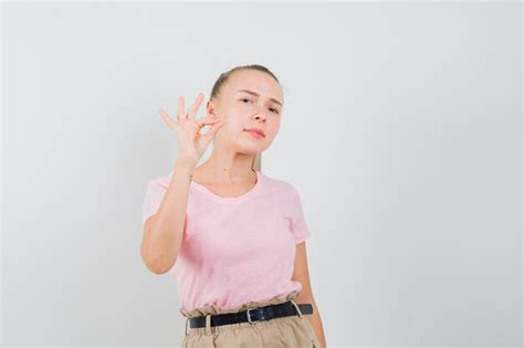 Fille blonde faisant un geste ok en t shirt pantalon et à la vue de