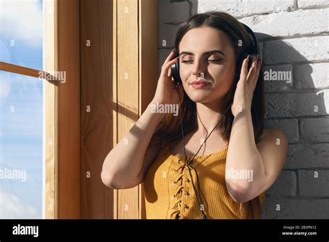 Beautiful Girl Enjoying Listening To Music While Leaning On The Wall