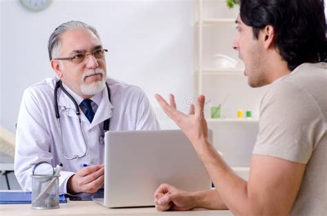 El Hombre Joven Que Visita Al Viejo Doctor De Sexo Masculino Imagen De