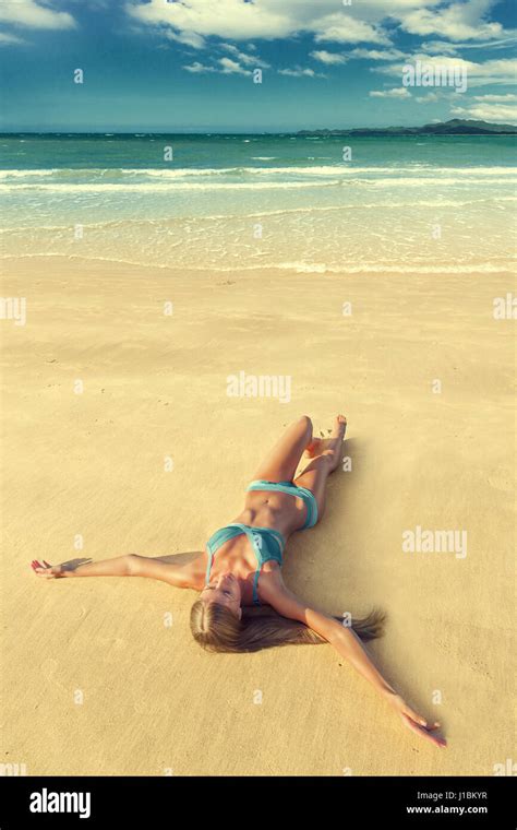 Belle jeune femme en bikini bleu allongé sur le sable à la mer tropical