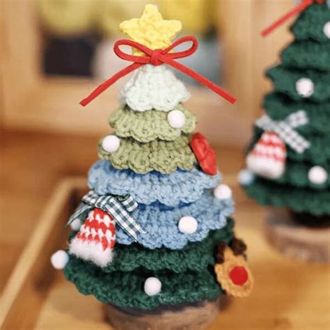 Small Crocheted Christmas Trees Sitting On Top Of A Wooden Table Next