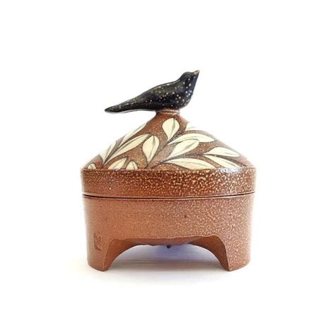 A Small Ceramic Box With A Bird On Top