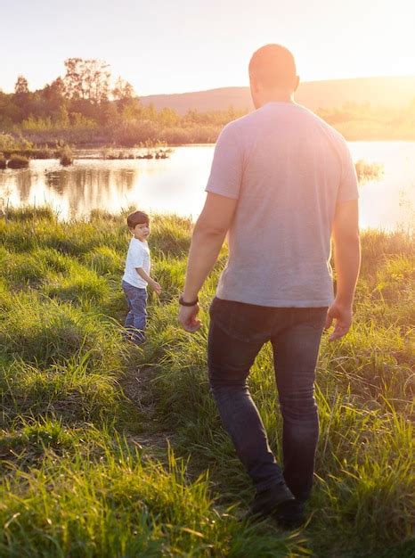 Uma criança pequena e o pai estão caminhando ao longo de um caminho no