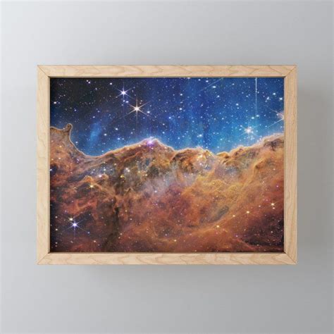 An Image Of The Sky With Stars In It Framed On A Wall Above A Shelf