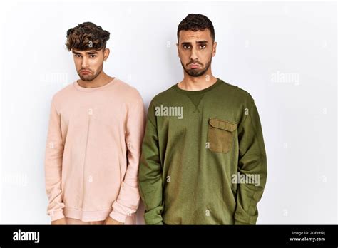 Jeune couple gay debout sur fond blanc isolé déprimé et s inquiéter de la détresse pleurant en