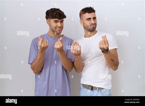 Homosexual Gay Couple Standing Over White Background Doing Money Gesture With Hands Asking For