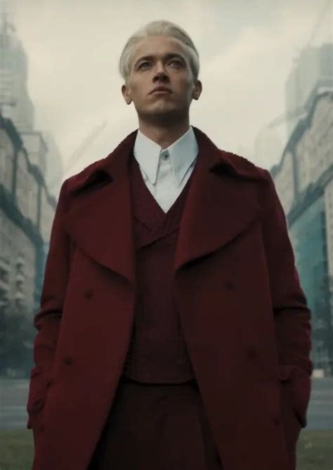 A Man In A Red Coat Is Standing In The Middle Of A City With Tall Buildings