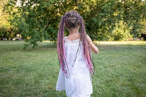 Ein Mädchen mit dunklen Augen mit geflochtenen Afro Zöpfen geht im Park